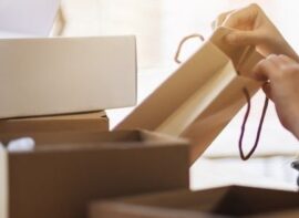 a woman opening and looking inside shopping bag with postal parcel box on the table at home for delivery and online shopping concept
