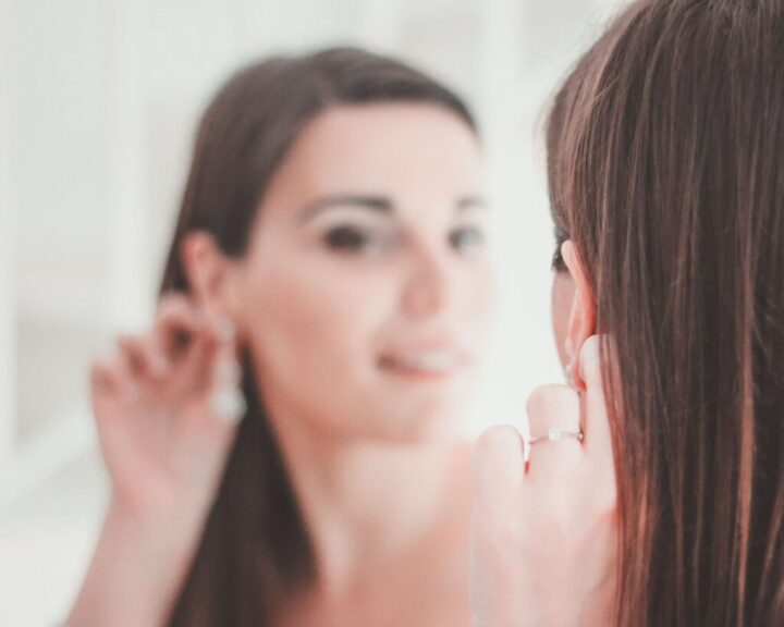 Young bride at the mirror with an earring